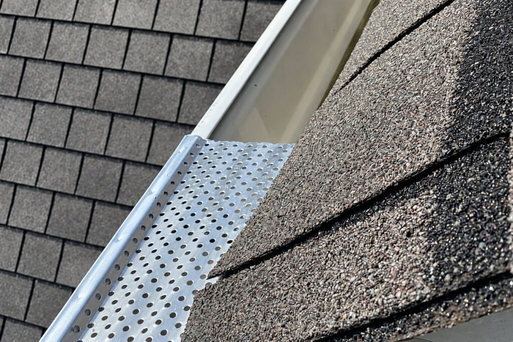 Perforated gutter guard installed under the roof shingles