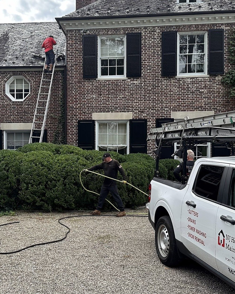 NJHMS crew and work truck at a brick home during a gutter cleaning