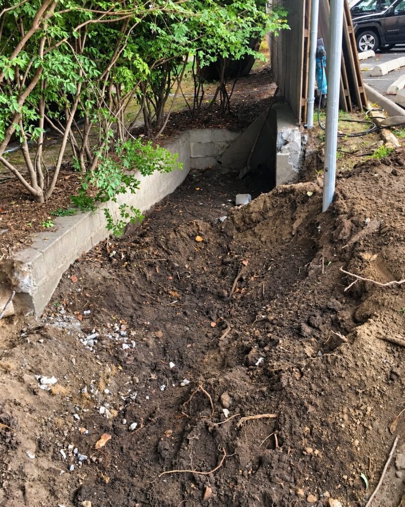Soil dug out around a failed underground drain line before repair