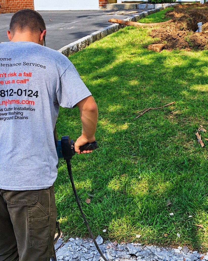 NJHMS technician working on an underground drain line beside the lawn
